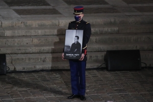 A Republican Guard holds a portrait of Samuel Paty