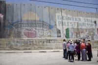A Fatah representative addresses the group beside the security wall.